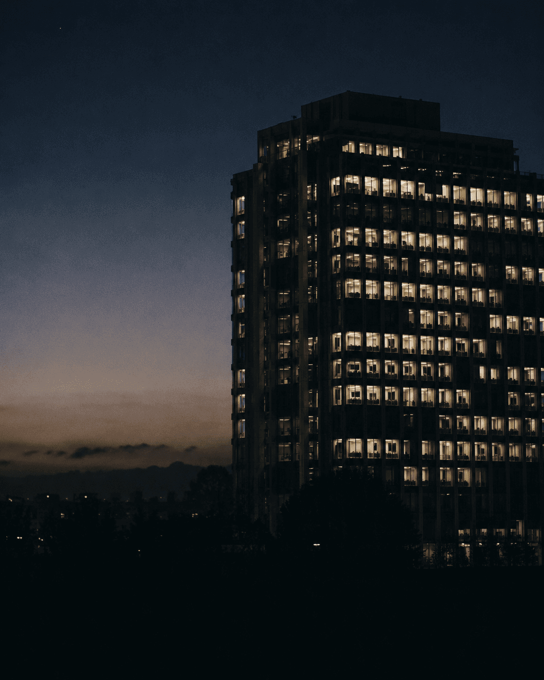 Nairobi office tower at dusk, illuminated facade grid against indigo sky